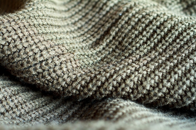 Close-up olive color knitted sweater made of natural wool texture, wavy folds, 