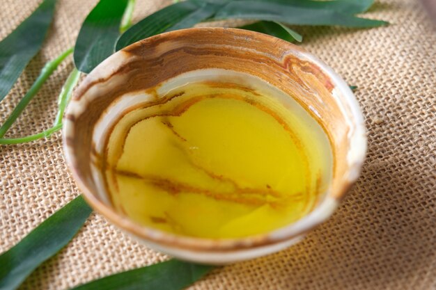 Close up of olive oil in a container and leaf on table