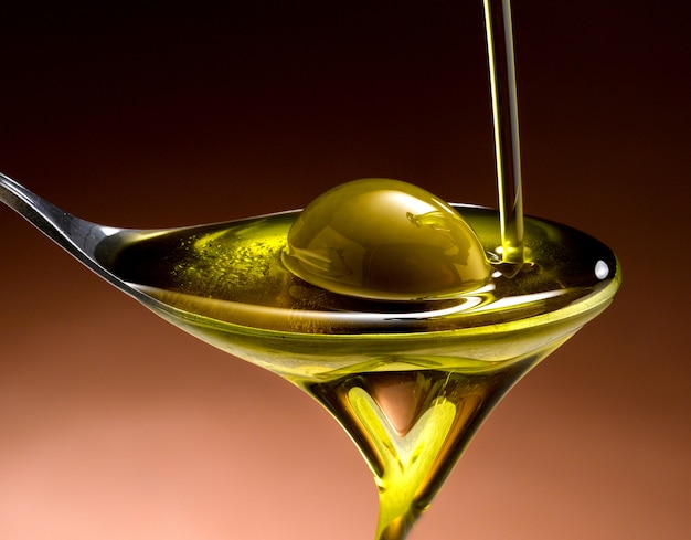 close up of olive oil poured into a spoon with olive