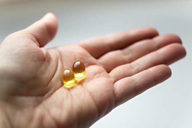 Photo close up omega 3 vitamin capsule in hand capsule fish oil in hand useful supplement healthy food