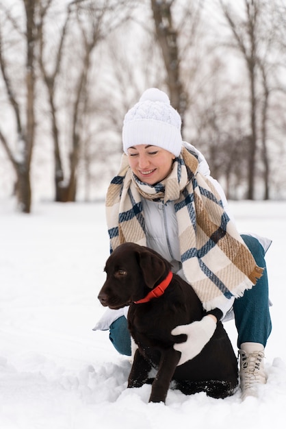 Фото Крупным планом счастливая мать играет в снегу с собакой