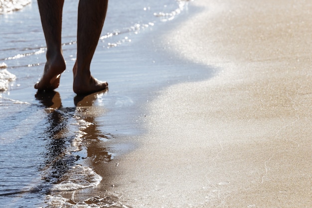 Крупным планом на движущихся ног человека, идущего на пляже.