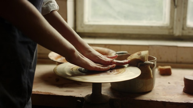 Close-up onbekende vrouw die zich voorbereidt op het werken met natte klei in een atelier klei kunstenaar die vrouwelijke pottenbakkers handwerk in een studio leert Onherkenbaar meisje dat handwerk in pottenbakkerij leert