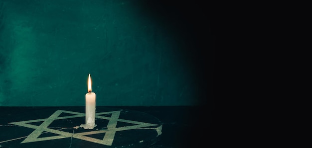 Photo close up one burning candles and the star of david against on a green background wall