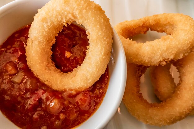 Close up onion rings and tomatoe sauce in little plate