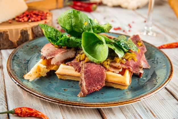 Close-up op belgische wafels met rundvlees pastrami en greens op de houten tafel