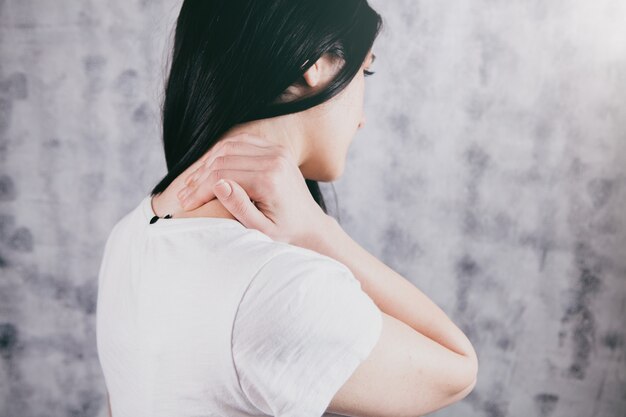 Close-up op de hand van een vrouw die haar nek masseert. de nek van het meisje doet pijn