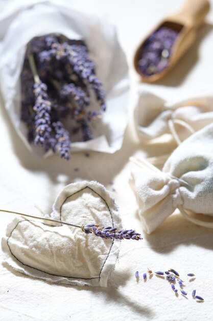 Close-up op droge lavendelbloemen in wit calqueerpapier Handgemaakte lavendelzakjes op katoenen tafelkleed Rustieke decoraties met weinig impact Houten lepel met droge lavendelbloemen Lavendelolie