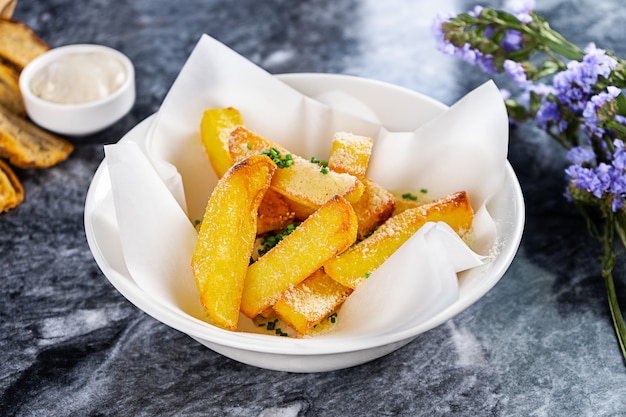 Close-up op frietjes met saus, knoflook en kaas in ambachtelijke papier