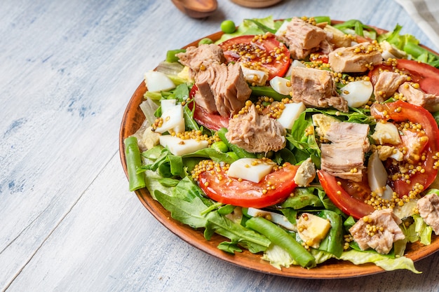 Close-up op grote plaat met smakelijke salade: tomaat, fetakaas, geroosterde vleeskip, asperges en groenten