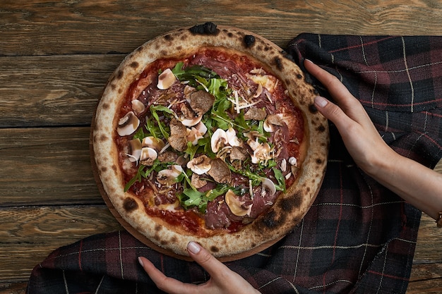 Close-up op heerlijke versgebakken kleine pizza met gesmolten kaas, champignons en basilicum.