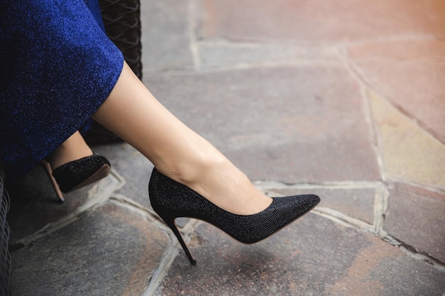 Close-up op mooie vrouwelijke benen in schoenen met een blauwe rok in een straatcafé