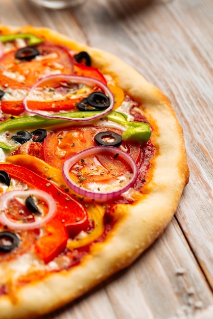 Close-up op plantaardige pizza met olijven en peper op de houten tafel