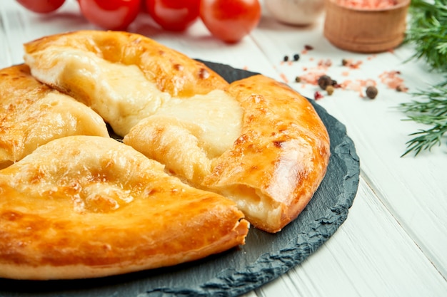 Close-up op smakelijke traditionele Khachapuri - gesloten gebakken taart gevuld met gesmolten zoute kaas (suluguni). Georgisch eten