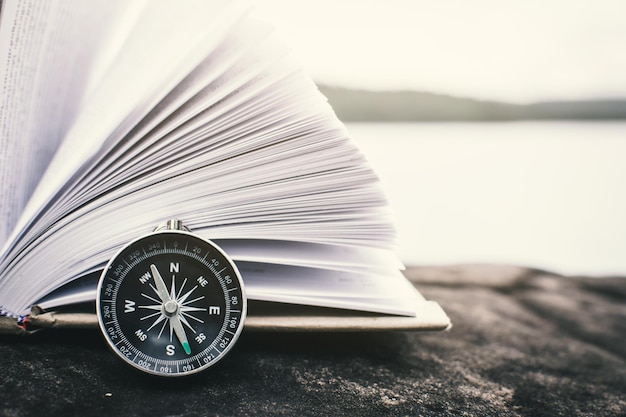 Close-up of open book and compass by lake