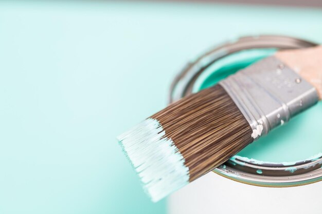 Close up of open can with blue paint and paint brush.