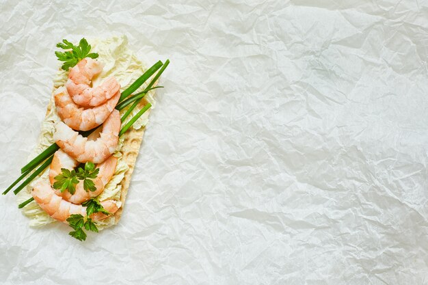 Close up of open sandwich with sea prawns, onions on white background