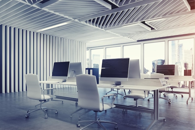 Close up of an open space office interior with gray wooden walls, concrete floor and two rows of computer tables along a wall and a panoramic window. 3d rendering mock up