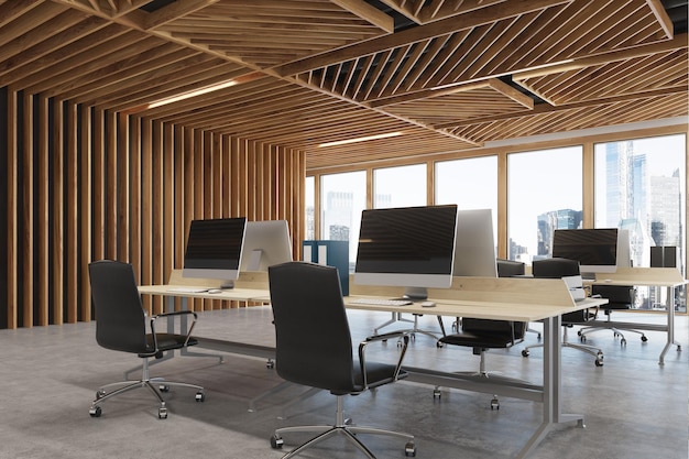 Close up of an open space office interior with wooden walls, concrete floor and two rows of computer tables along a wall and a panoramic window. 3d rendering mock up