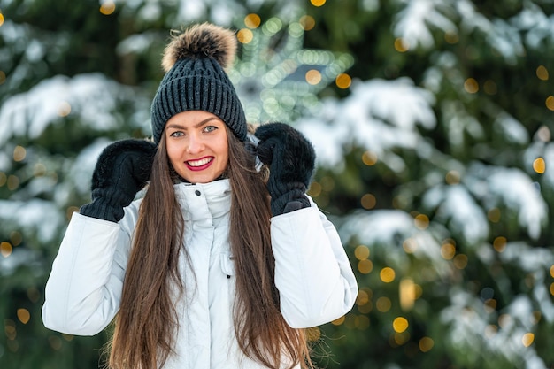 Close-up openluchtportret van zeer mooie jonge vrouw over de achtergrond van kerstboomlichten