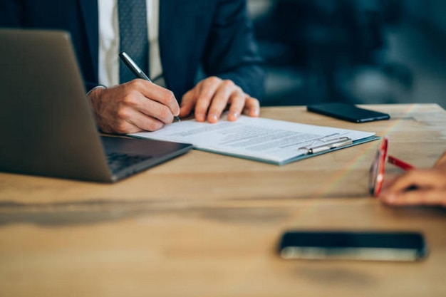 Close-up opname van twee zakenlieden die papierwerk invullen in een kantoor