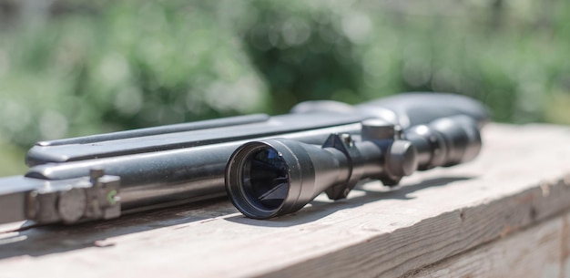 Close-up optische zicht van een geweer Een geweer met een optische zicht ligt op een versleten houten plank Selectieve aandacht
