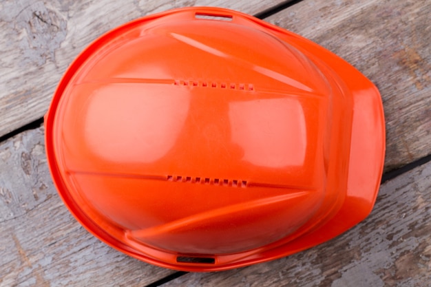 Close up orange constructor's helmet. old aged table on the background