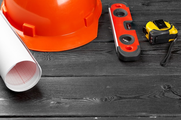 Close up orange hardhat and variety of repair tools with copy space in the middle over wooden 