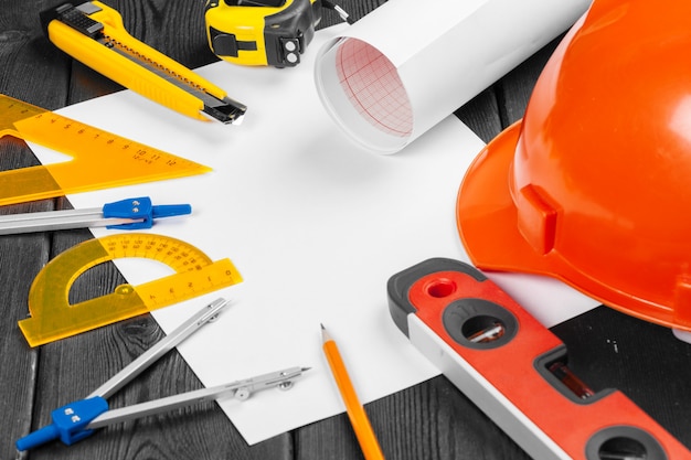 Close up orange hardhat and variety of repair tools with copyspace in the middle over wooden  