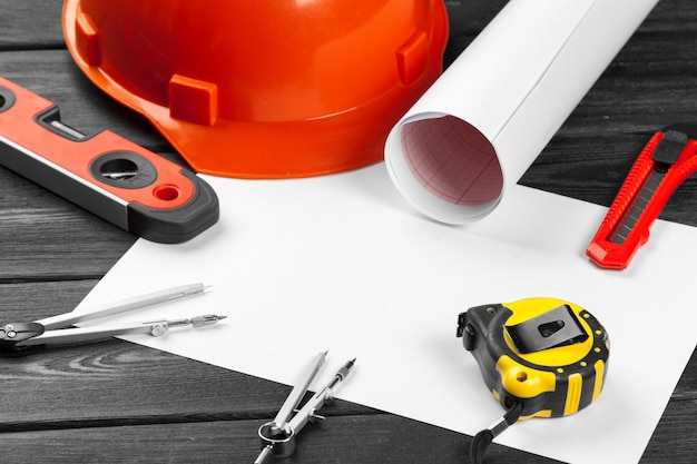 Photo close up orange hardhat and variety of repair tools with copyspace in the middle over wooden