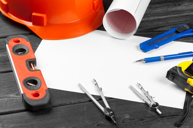 Photo close up orange hardhat and variety of repair tools with copyspace in the middle over wooden