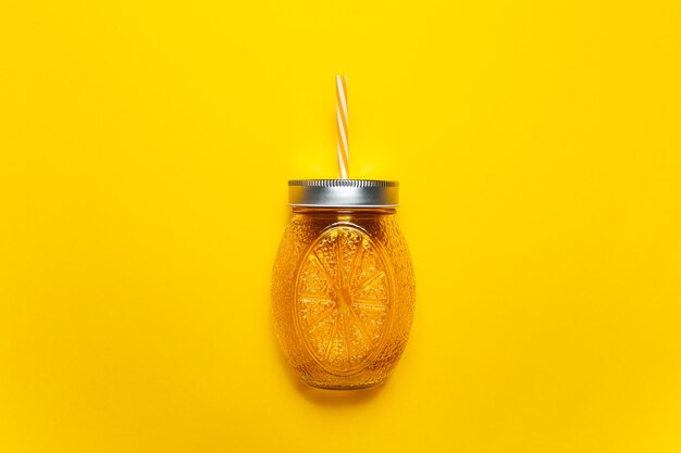 Close-up of orange juice glass mug with straw