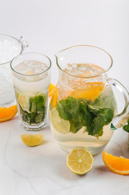 Close up on orange and lime lemonade in a jug and glass isolated