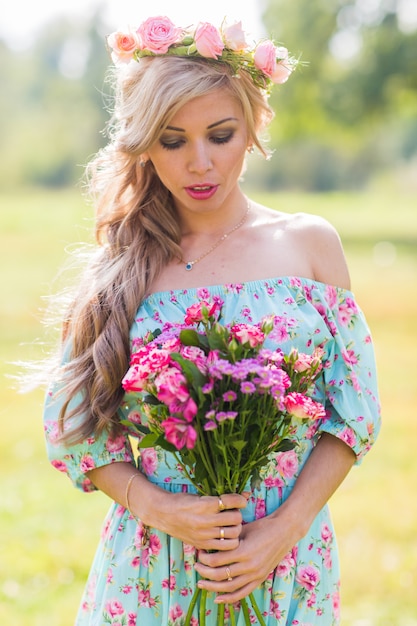 Close-up outdoor portrait of a beautiful blonde woman. attractive happy girl in a field with bouquet of flowers.