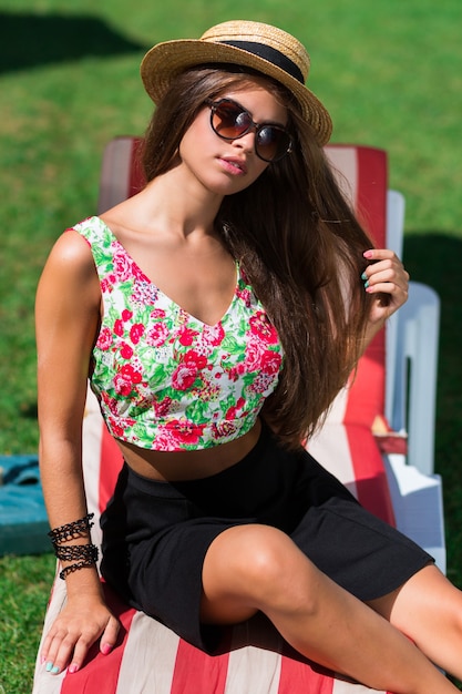 Close up outdoor portrait of young woman smiling , sitting on green fresh grass in sunny spring park