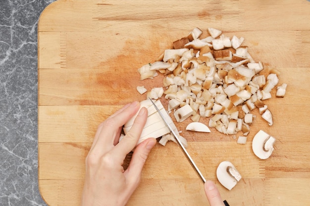 Close up overhead view of cutting champignon on wooden cutting board