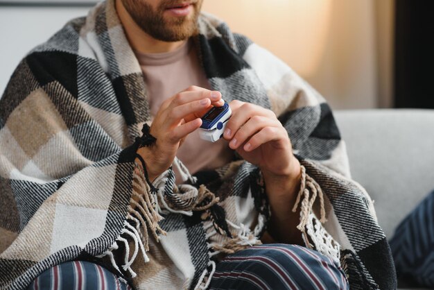 Close up of oximeter on hand of ill person resting while\
measuring oxygen saturation and pulse pressure to check virus\
symptoms sick adult using device for healthcare treatment