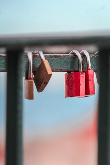 Photo close-up of padlocks hanging on railing against sky