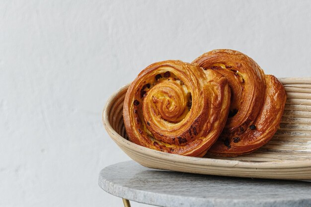 Primo piano di pain aux raisins o rotolo di caffè di traduzione koffiebroodje olandese su un tavolo bianco