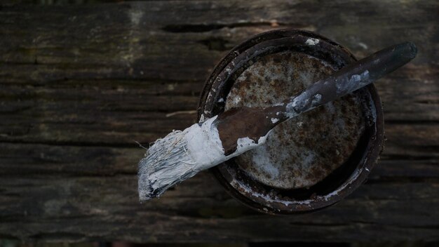 Photo close up of paint can with brush on wooden table