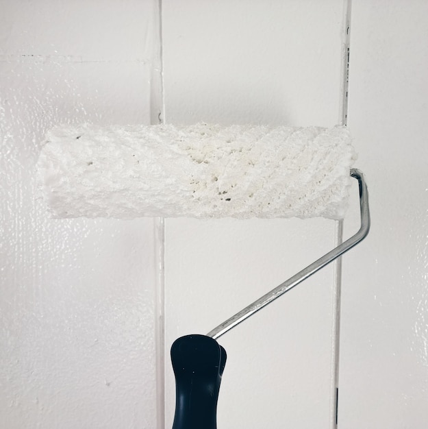 Photo close-up of paint roller on white wall