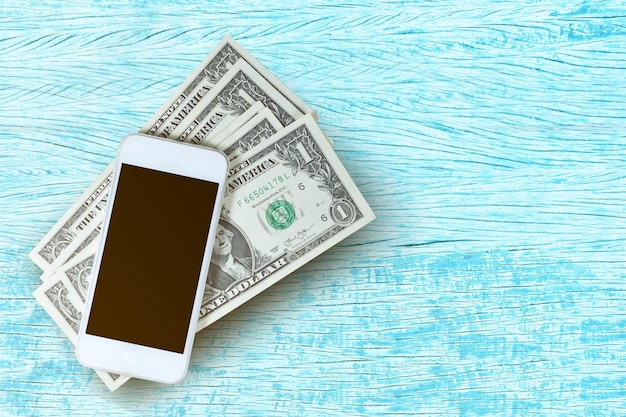 Photo close-up of paper currencies with smart phone on table