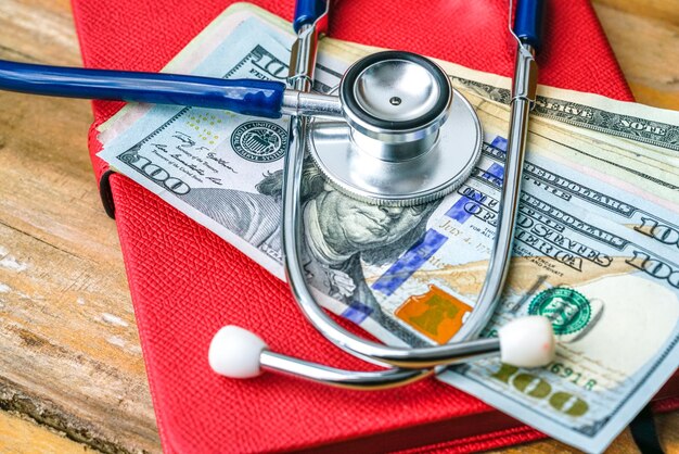 Close-up of paper currencies with stethoscope on wooden table