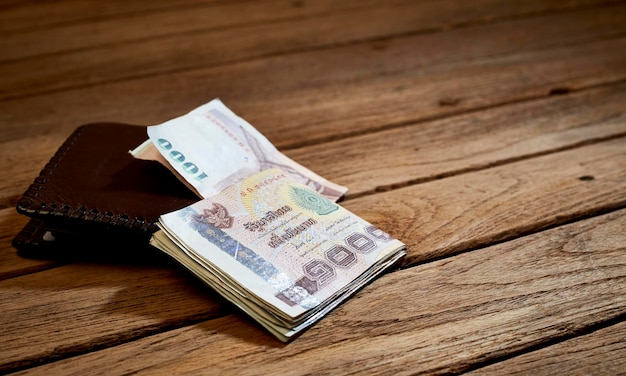 Close-up of paper currency with wallet on wooden table