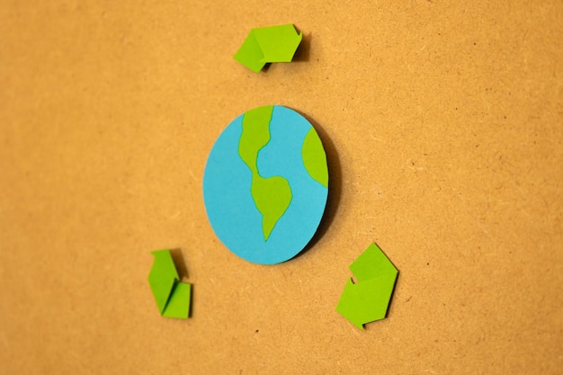 Close up of paper planet Earth with recycling signal on a board