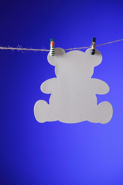 Photo close-up of paper teddy bear hanging over blue background