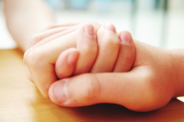 Foto close-up di genitore e figlio che si tengono per mano sul tavolo