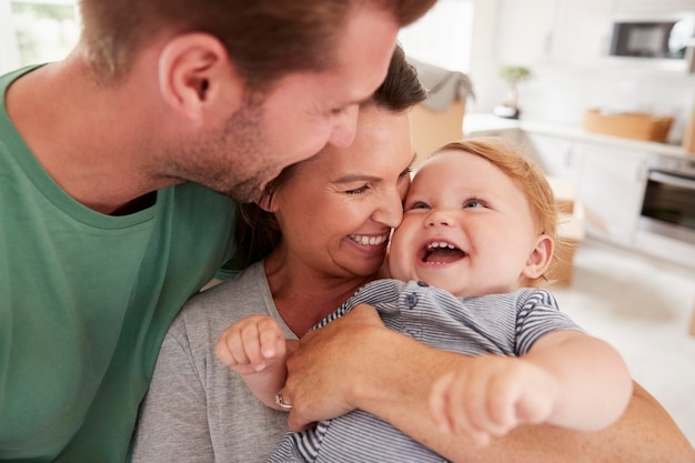 Крупный план родителей, обнимающих счастливого маленького сына дома