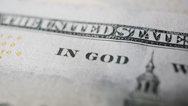 Close-up of part of slogan In God We Trust in the US banknote. Business and finance concept. Macro photography, selective focus.