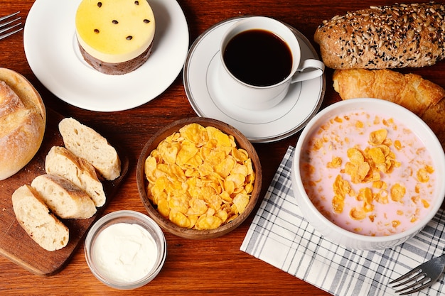 Foto primo piano di torta di frutto della passione, pane tostato, caffè, yogurt, cereali.